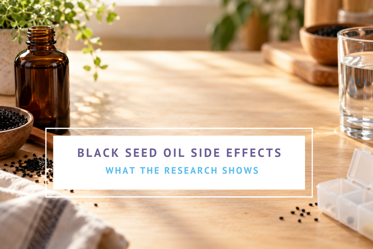 Spoonful of black seed oil beside black cumin seeds, a dark glass bottle, and a pill organizer on a kitchen counter