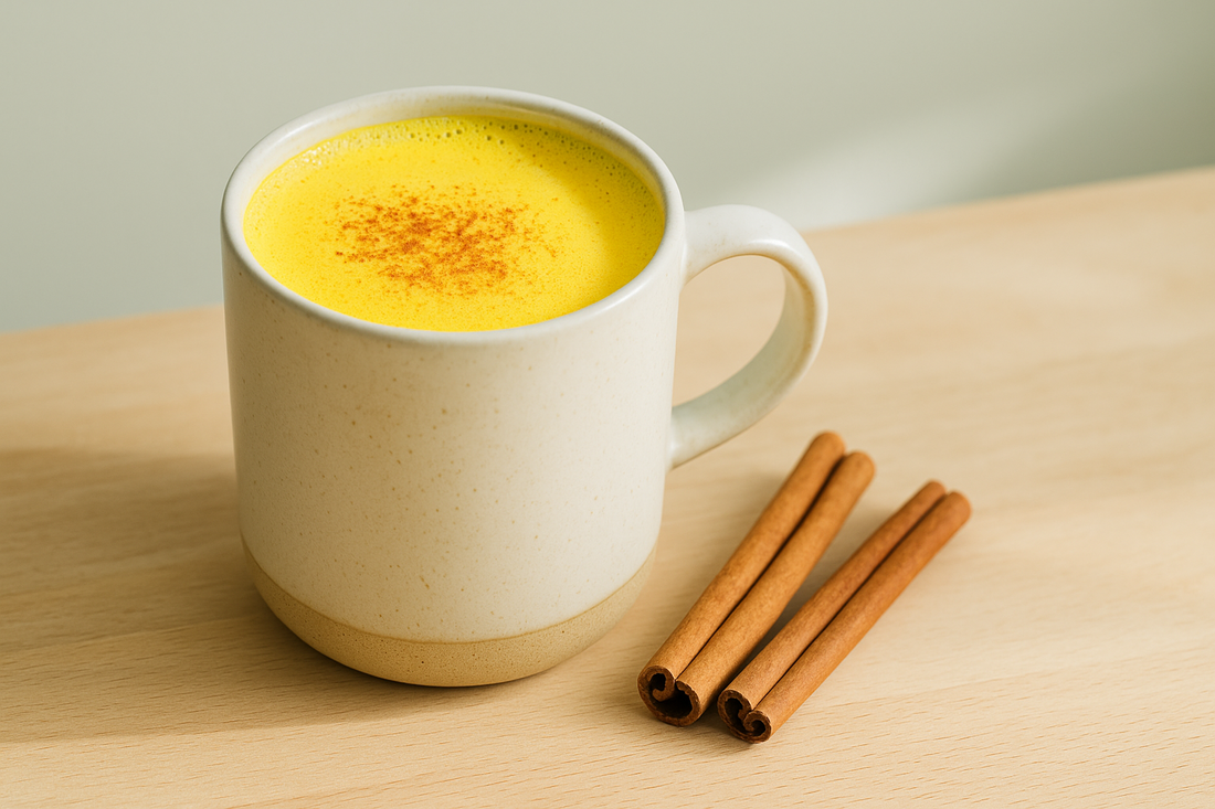 Vibrant golden-yellow turmeric latte with Organic Gelatinized Black Maca in ceramic mug with cinnamon sprinkles on top and cinnamon sticks on wooden surface with natural lighting